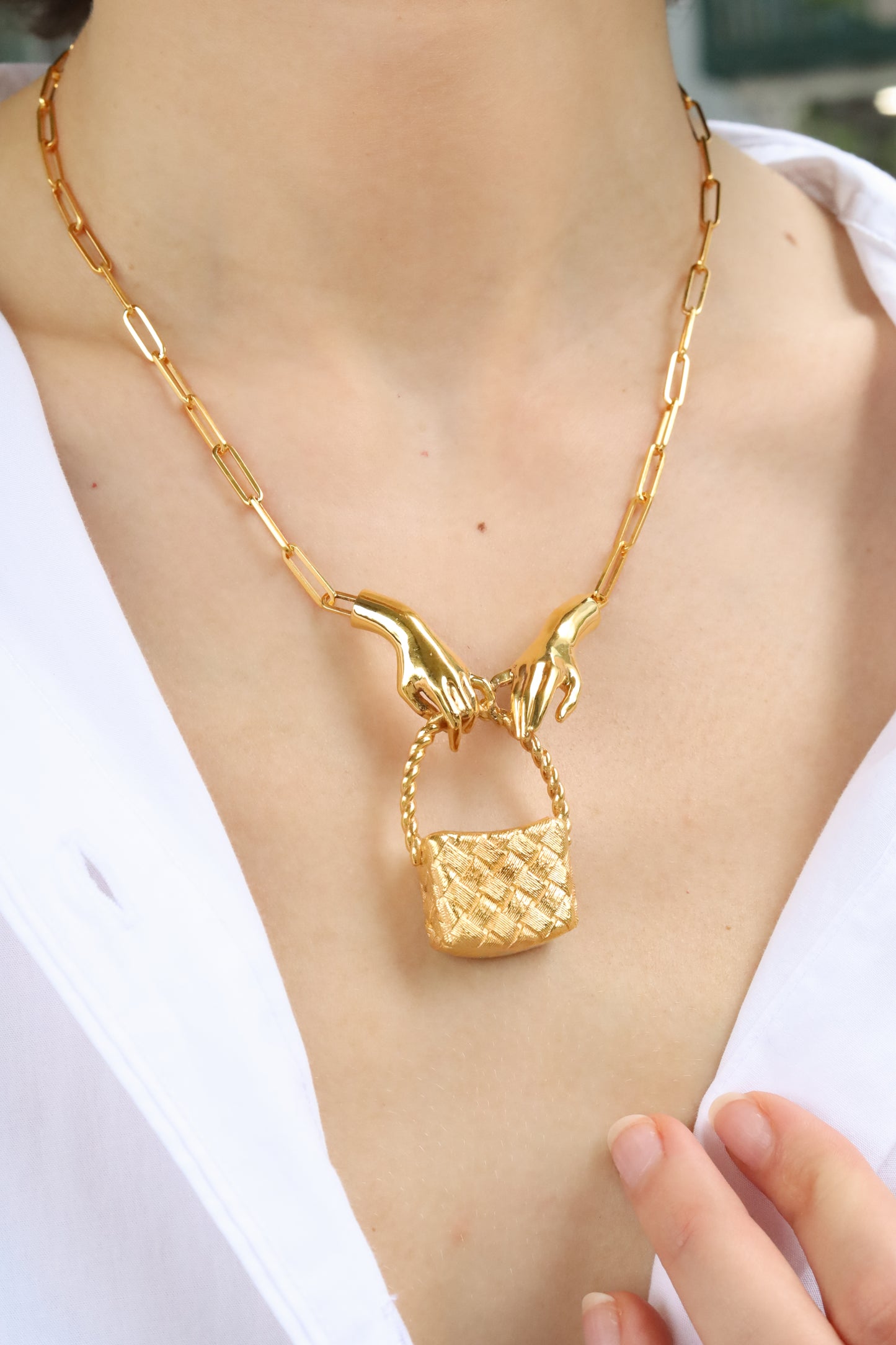 Gold necklace with a unique pendant on a person wearing a white shirt.