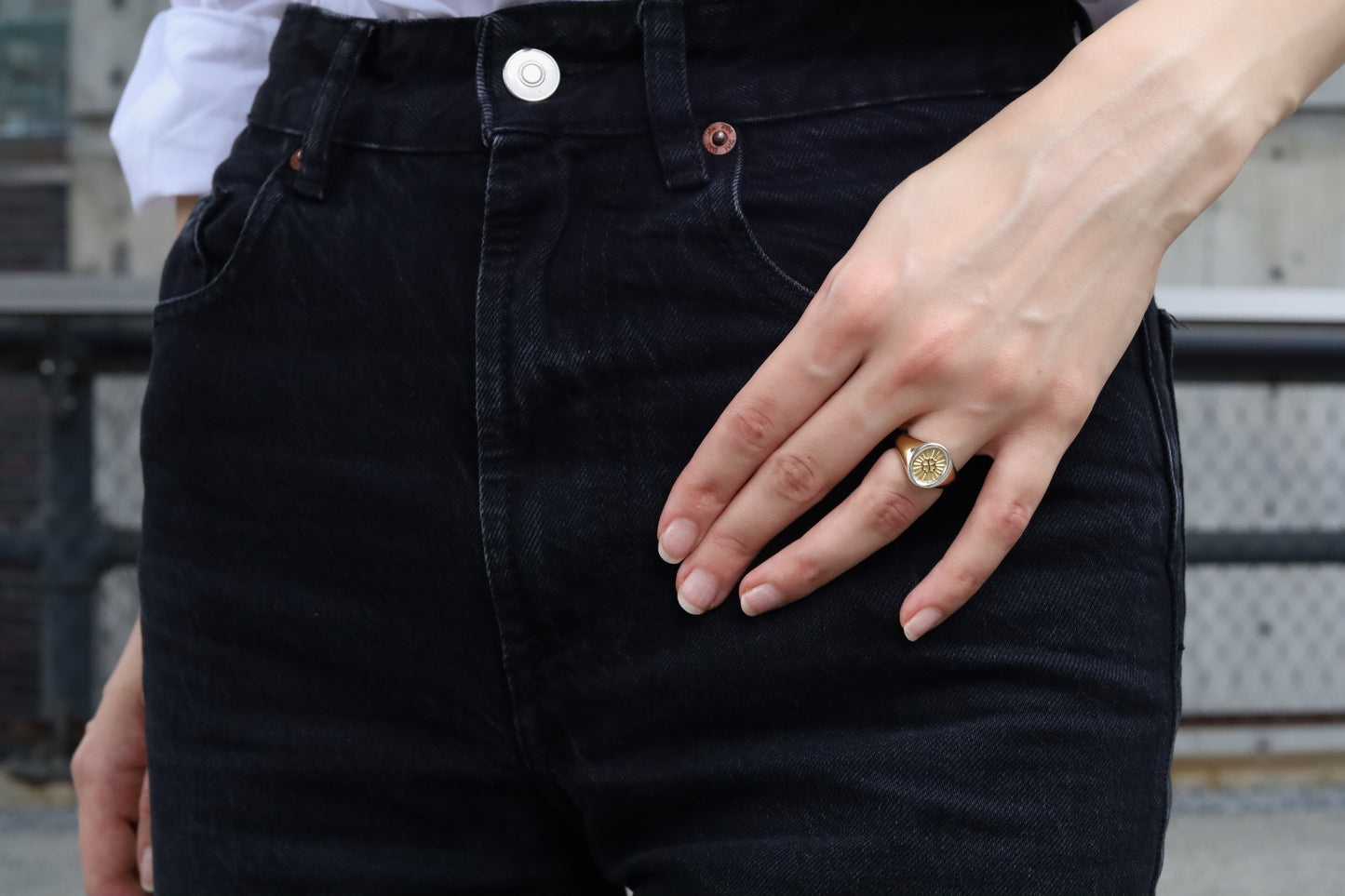 Person wearing black jeans with a close-up of a hand and ring.