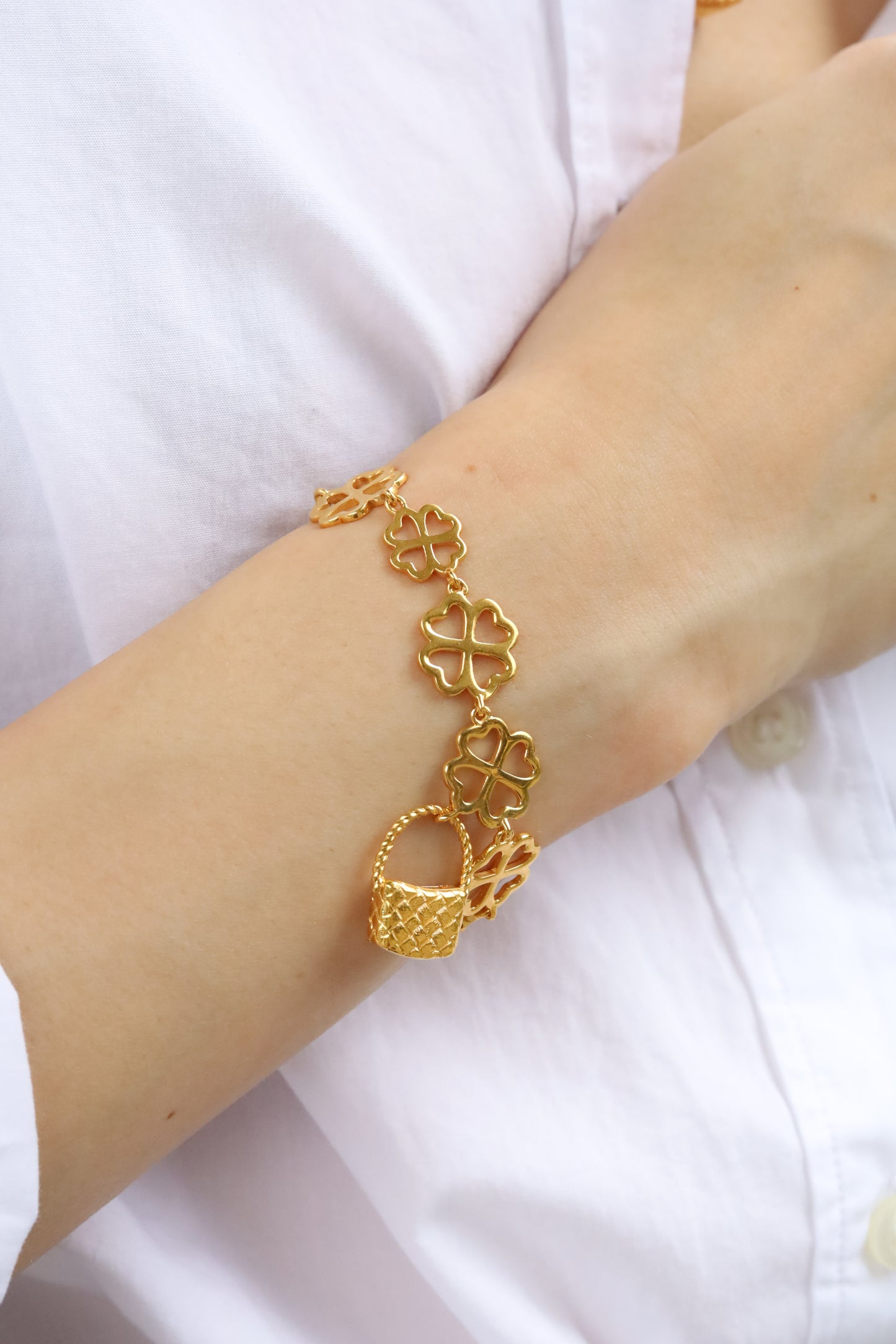 Gold bracelet on a person's wrist against a white background