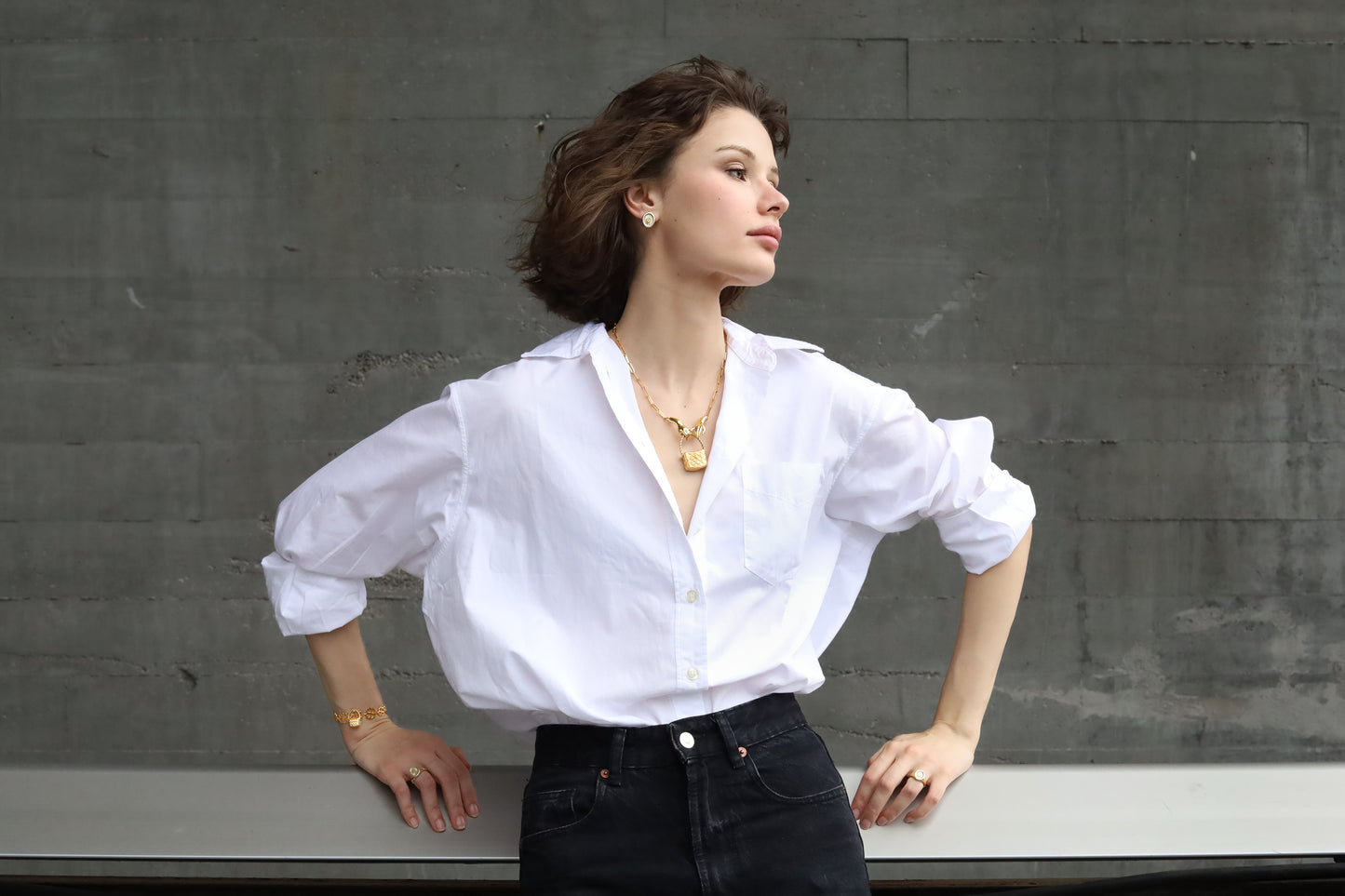 Woman wearing a white blouse with puffed sleeves against a gray wall.