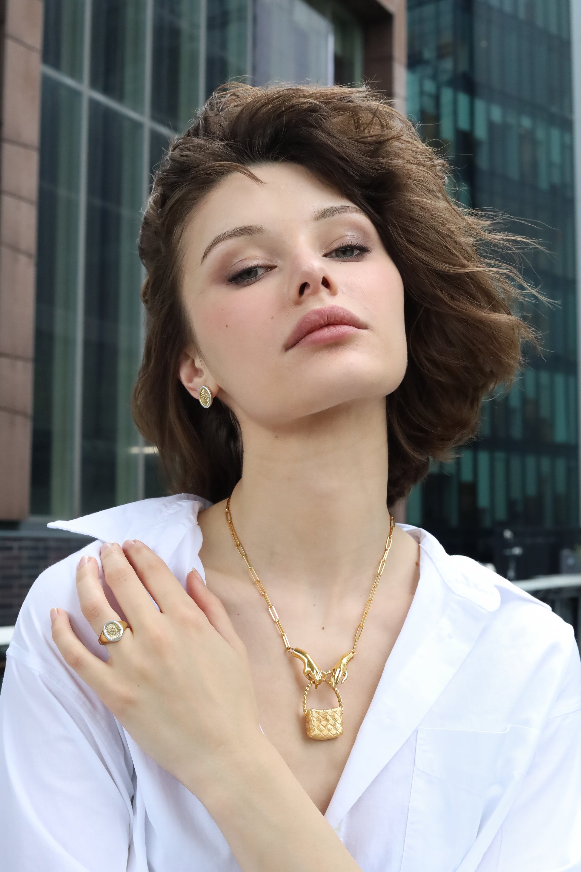 Woman wearing a gold necklace and ring with a cityscape background