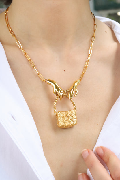 Gold necklace with a unique pendant on a person wearing a white shirt.