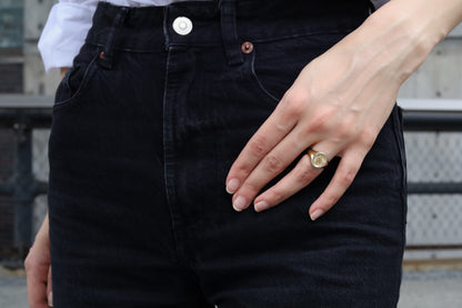 Person wearing black jeans with a close-up of a hand and ring.