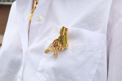 Gold brooch with a pendant on a white shirt