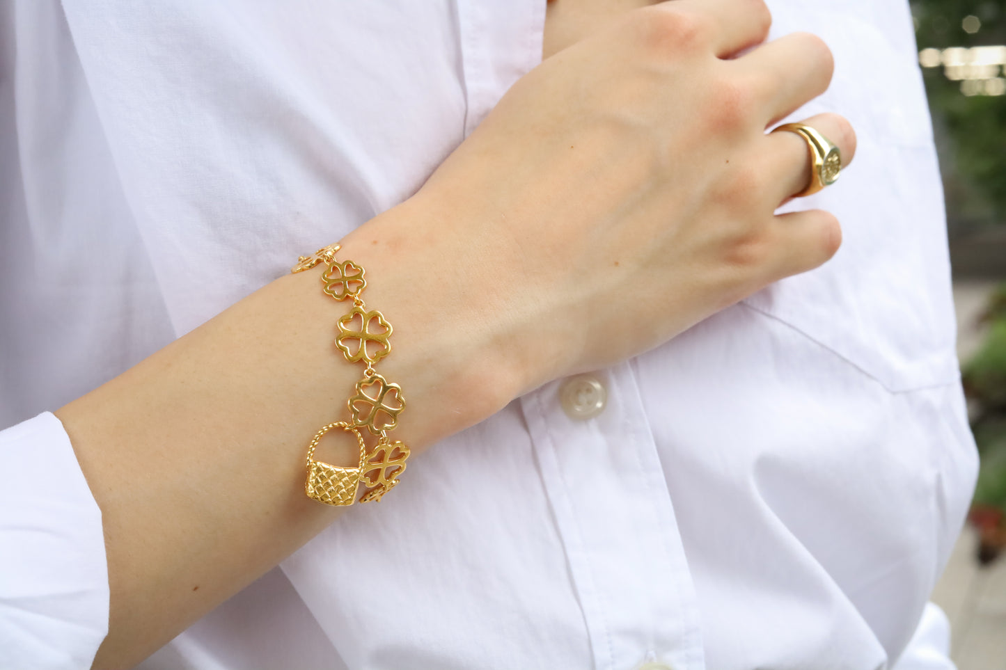 Jenna London gold bracelet on a woman's wrist with a blurred background